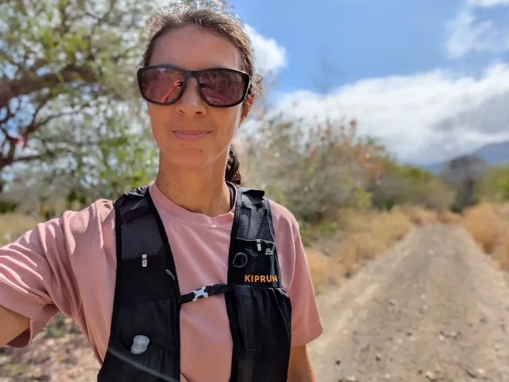 Portrait de Célia Duwicquet en tenue de trail dans un chemin caillouteux bordé de végétation